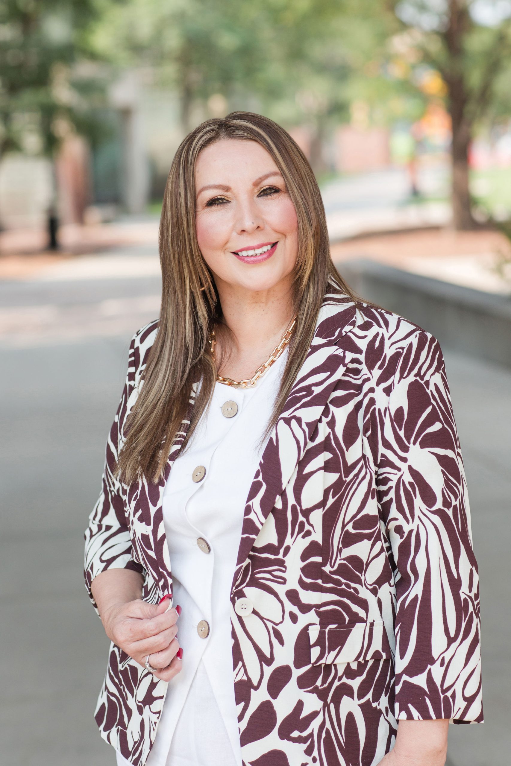 Elizabeth Leyva, mobile notary and certified signing agent, smiling outdoors in professional business attire.